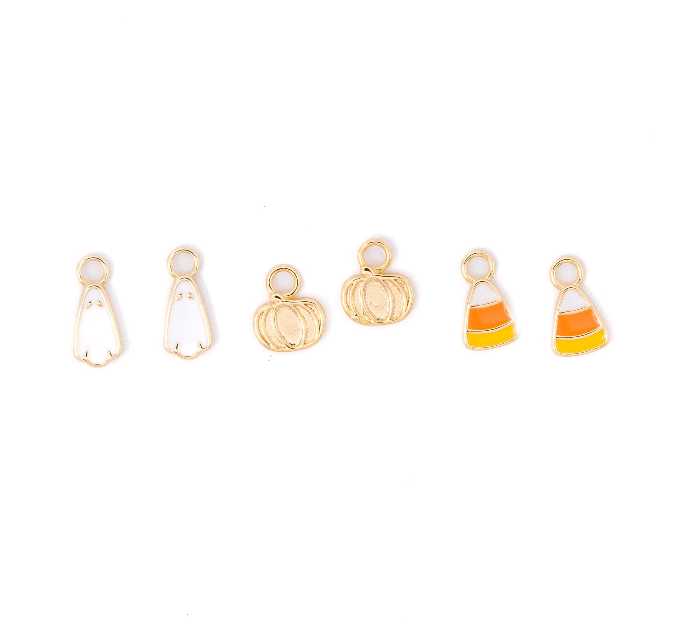 Six small gold-tone charms with white, orange, and yellow enamel details, including ghost, pumpkin, and candy corn designs, arranged on a plain white background.