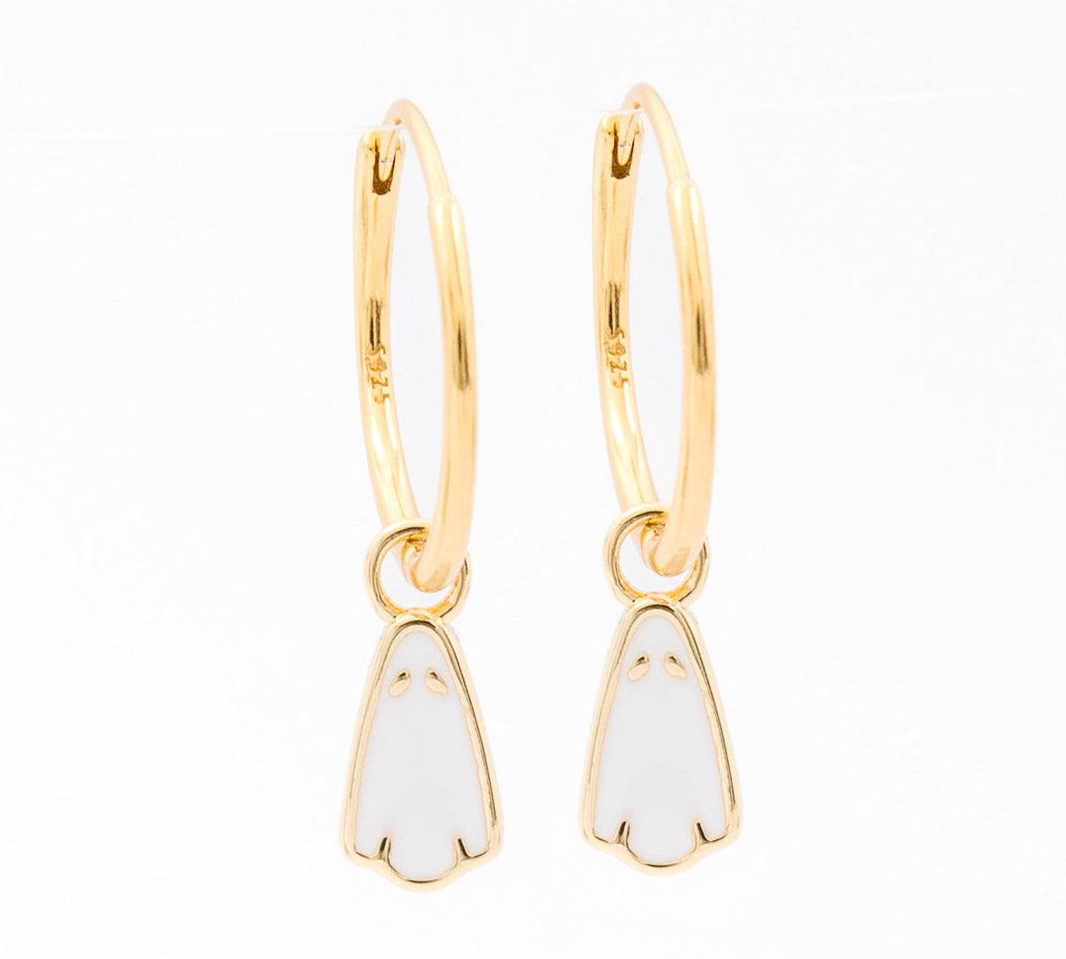 A pair of gold huggie hoop earrings with small white enamel penguin charms, shown on a plain white background.