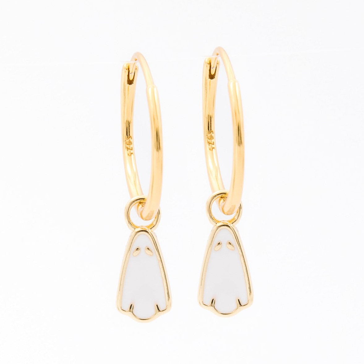 A pair of gold huggie hoop earrings with small white enamel penguin charms, shown on a plain white background.