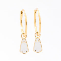 A pair of gold huggie hoop earrings with small white enamel penguin charms, shown on a plain white background.