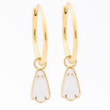 A pair of gold huggie hoop earrings with small white enamel penguin charms, shown on a plain white background.