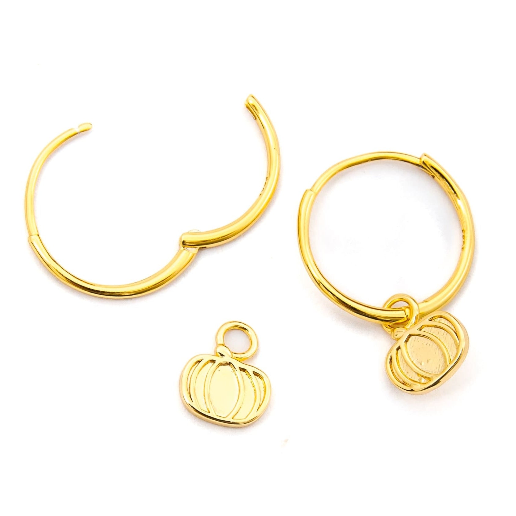 Gold-toned hoop earrings with small pumpkin charms, displayed on a clean white background.