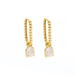 A pair of gold huggie hoop earrings with a small white enamel pendant of a tombstone that says RIP on a plain white background.