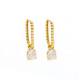 A pair of gold huggie hoop earrings with a small white enamel pendant of a tombstone that says RIP on a plain white background.