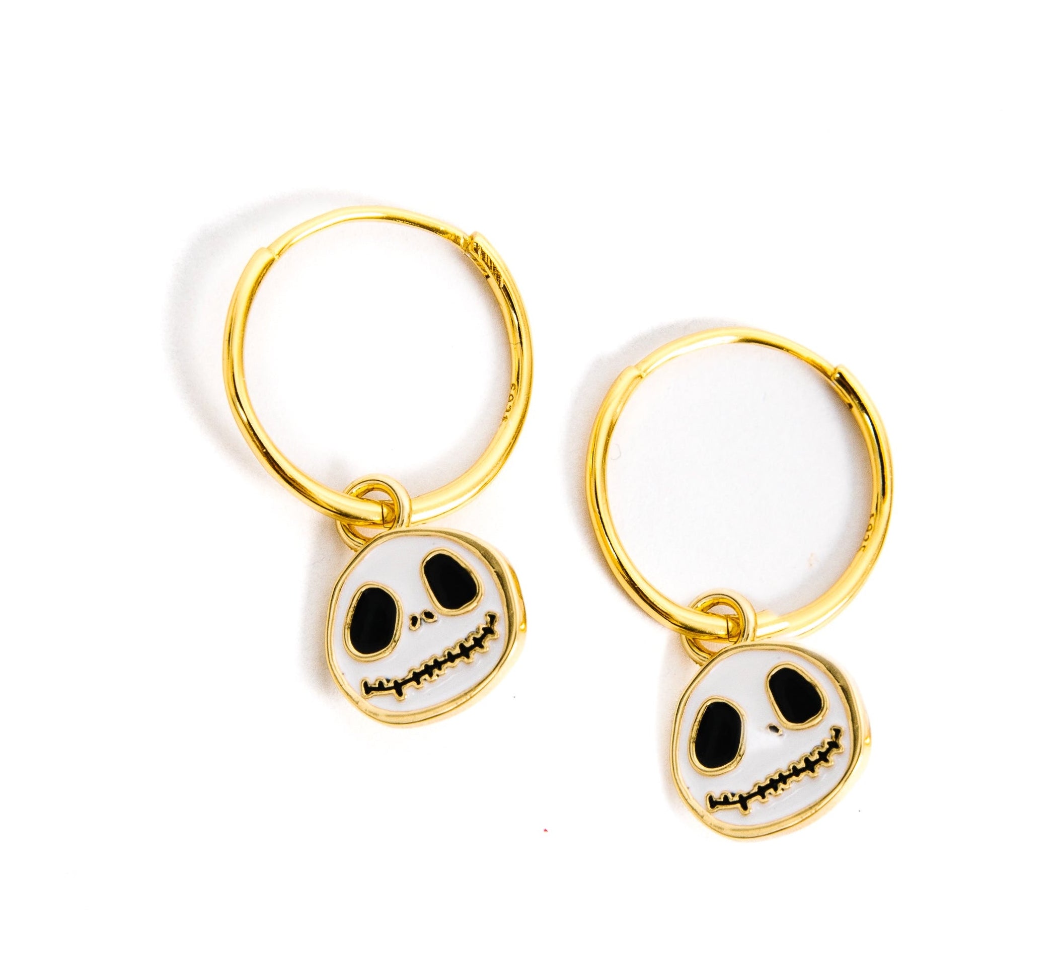 A pair of gold hoop earrings with dangling skull charms, shown on a plain white background.