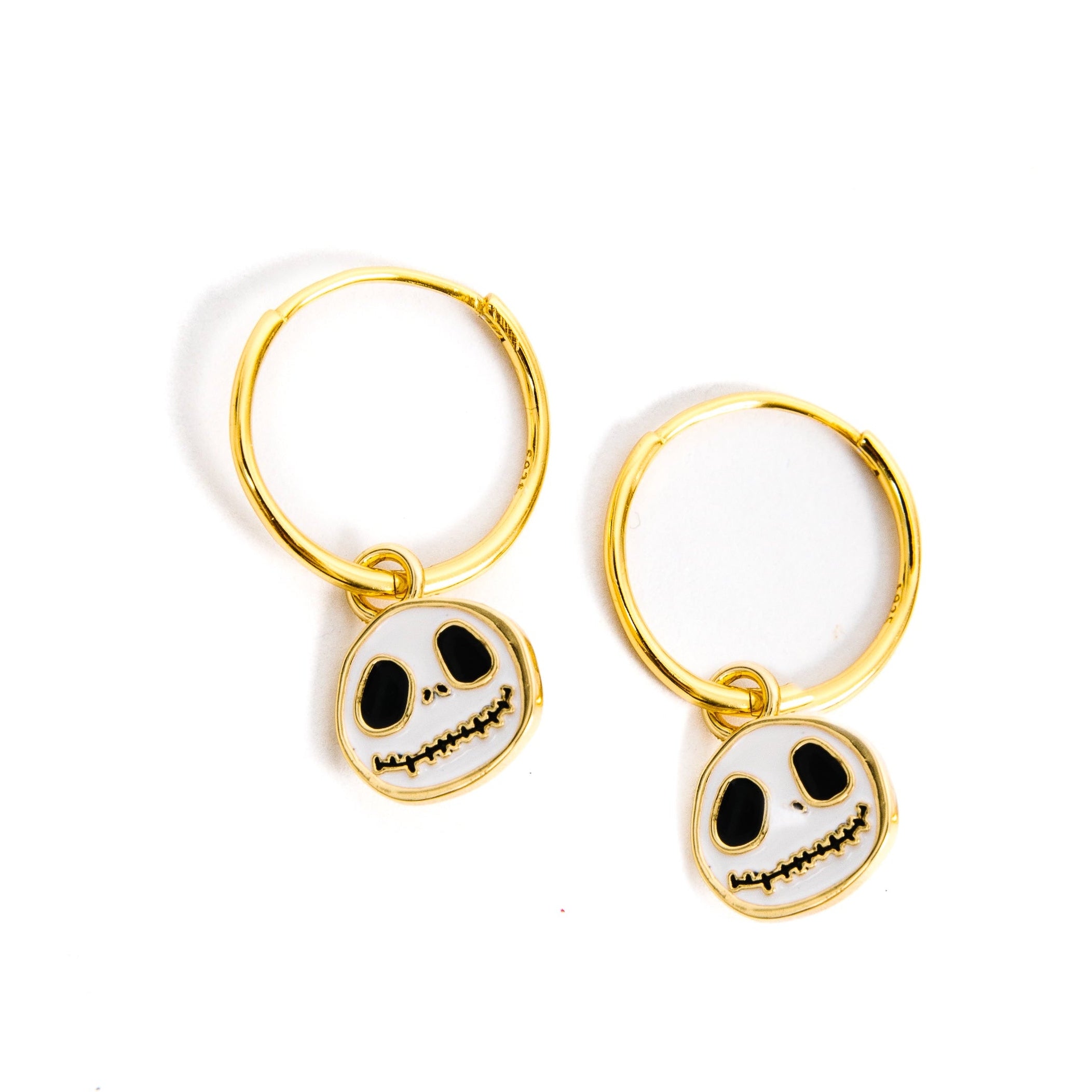 A pair of gold hoop earrings with dangling skull charms, shown on a plain white background.