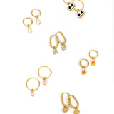 Six pairs of gold hoop earrings with various charms, including Jack Skellington, candy corn, tombstone, pink ghosts, white ghosts, and gold pumpkins, arranged on a plain white background.