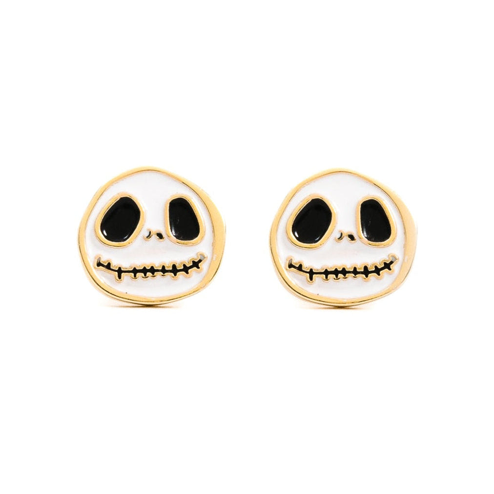 A pair of skull-shaped stud earrings with a white enamel face, black eyes and mouth details, and a gold-tone border, shown on a plain white background.